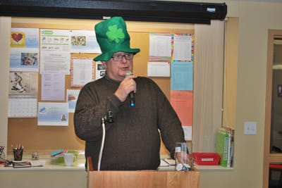 Resident dressed for St. Patrick's Day celebration speaking at a podium