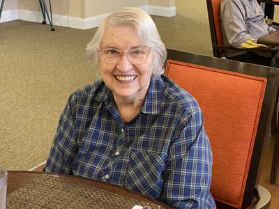 A smiling resident in a plaid shirt sitting in a common area