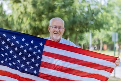 Senior resident holding a U.S. flag outdoors