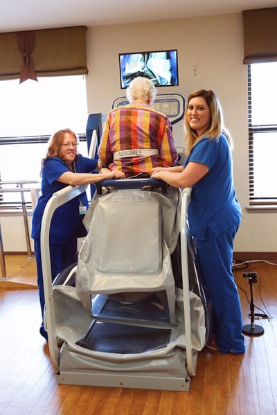 Therapist assisting a resident in rehabilitation equipment