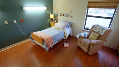 A cozy resident room with a bed and armchair