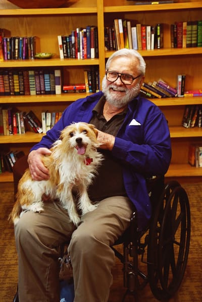 A resident smiling with a dog in a library setting