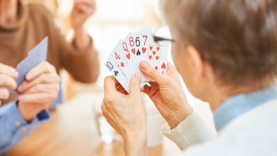 Seniors playing cards in a well-lit common area