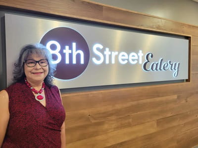 Resident posing in front of the dining area sign