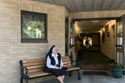 A resident sitting on a bench in a facility entrance area