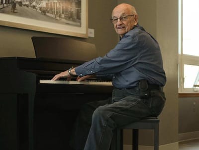 Senior playing piano in a common area