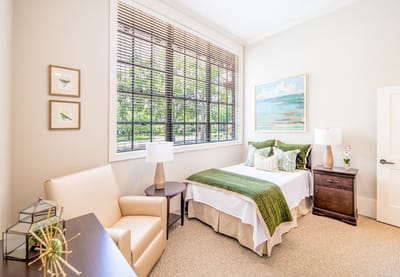 Bright private resident room with a bed and seating.