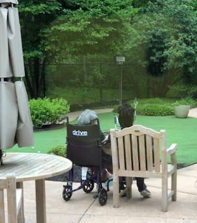 Two residents enjoying a garden space in wheelchairs