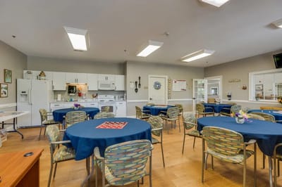 Bright activity room with round tables and chairs