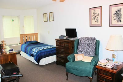 Cozy private room with bed and green chair