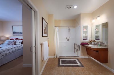 Modern bathroom with accessibility features and a bedroom visible