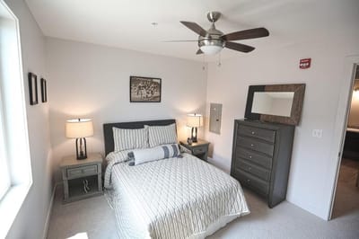 A well-decorated private resident room with a bed and dresser