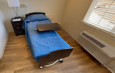 Private resident room with a bed and side table