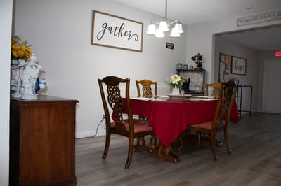 A cozy dining room with a red tablecloth and decorative signs