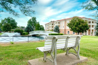Exterior view of a senior living facility near a pond