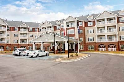 Exterior view of a senior living facility entrance with parked cars