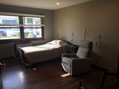 A private resident room with a bed and chair