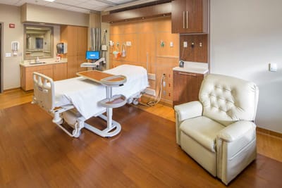 Interior view of a hospital room with a chair and hospital bed