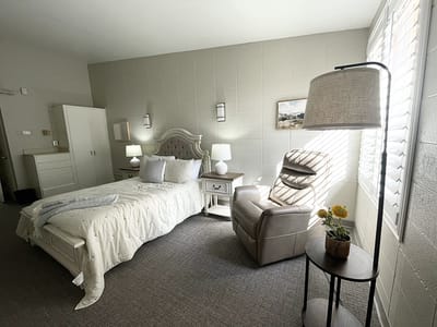 Bright interior of a resident room with a bed and chair