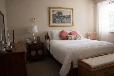 Cozy bedroom with bed, dresser, and artwork