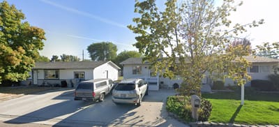 Exterior view of a residential care home with vehicles