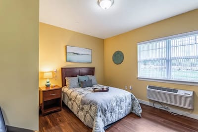 Cozy private room with a bed, nightstand, and window
