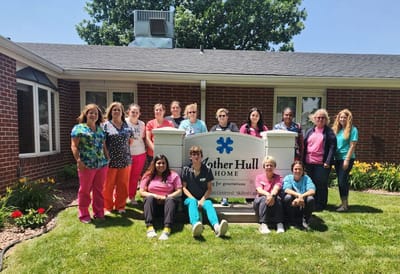 Staff members posing in front of the facility sign