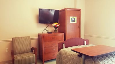 A cozy resident room with a bed, TV, and furniture