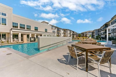 Outdoor pool area with seating and nearby buildings