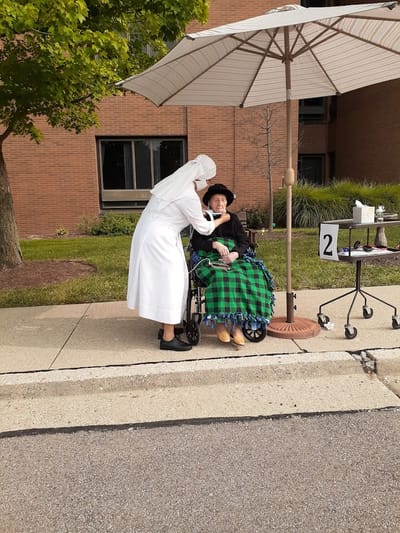 A caregiver assisting a resident outdoors at a senior facility
