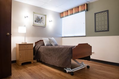 A well-furnished private resident room with a bed and lamp