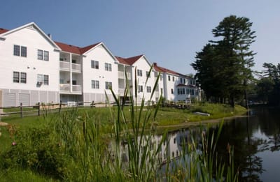 Exterior view of a senior living facility by a pond
