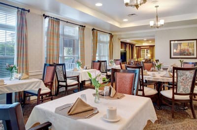 Bright dining room with neatly set tables and floral centerpieces