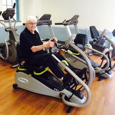 Senior man exercising on a NuStep machine in a fitness room