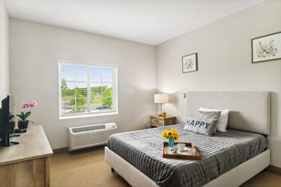 Cozy resident room with bed, flowers, and TV
