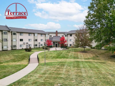 Exterior view of The Terrace Retirement Community with logo