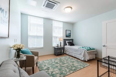 Brightly decorated private resident room with a bed and seating area