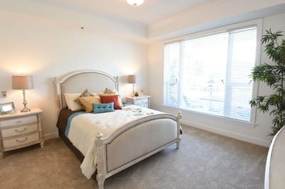 A well-decorated resident room with a cozy bed and natural light