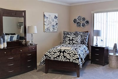 A private resident room with a bed and dresser