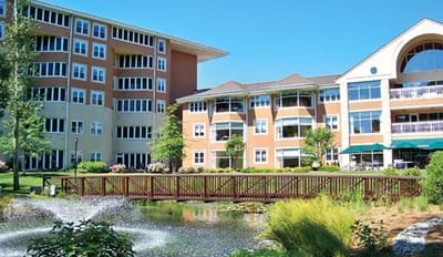 Exterior view of the facility with a pond and landscaping