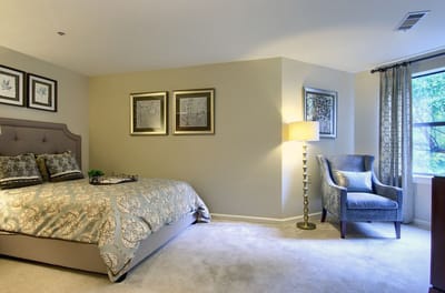 A well-furnished resident room with a bed and chair