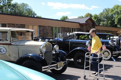 Resident using a walker near classic cars outside