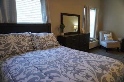 A well-furnished private bedroom with a bed and dresser