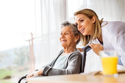 Caregiver interacting with an elderly resident indoors.
