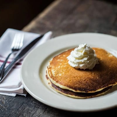 Plate of pancakes topped with whipped cream