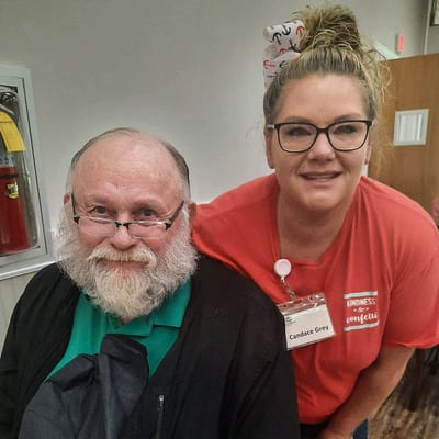 A staff member posing with a resident in a common area