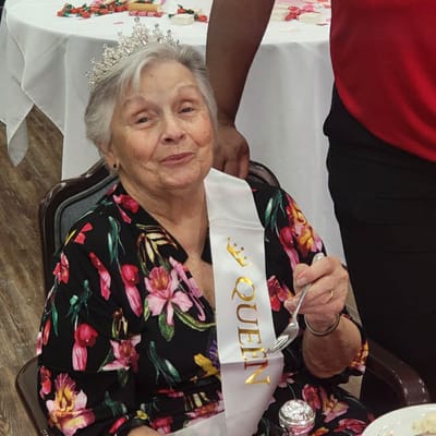 Resident celebrating with a crown and sash at a party