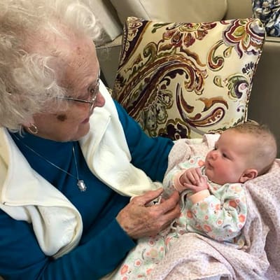 An elderly woman holding a baby in a cozy setting