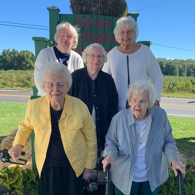 Five residents smiling in front of a sign