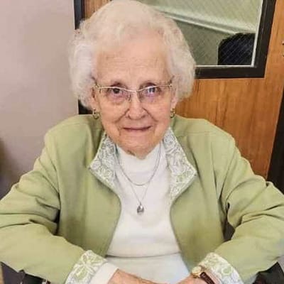 A smiling elderly woman sitting in a chair indoors